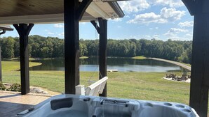 Una vasca idromassaggio sotto un pontile di legno con vista su un lago e sedie.