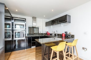 Enjoy cooking in this kitchen with a sleek island, ovens, and a large range hood.