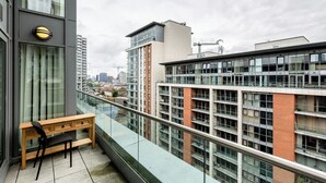 Een modern appartement met een balkon, een houten bureau en uitzicht op de stad.