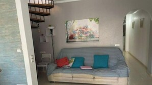 A modern living room with a sofa, a dining table, and a staircase. - Piso Bolnuevo Playa, muy Cerca de la Playa, al Lado Todos los Servicios, (Bolnuevo)