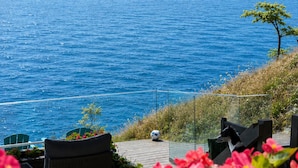 Vista al mar con una terraza de madera, sillas y un balón de fútbol.