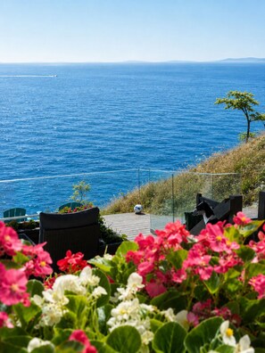 A seaside view with a wooden deck, chairs, and a soccer ball. - Waterfront Room with Private Bath and Deck Near Marina, Private Beach Access (Gibsons)