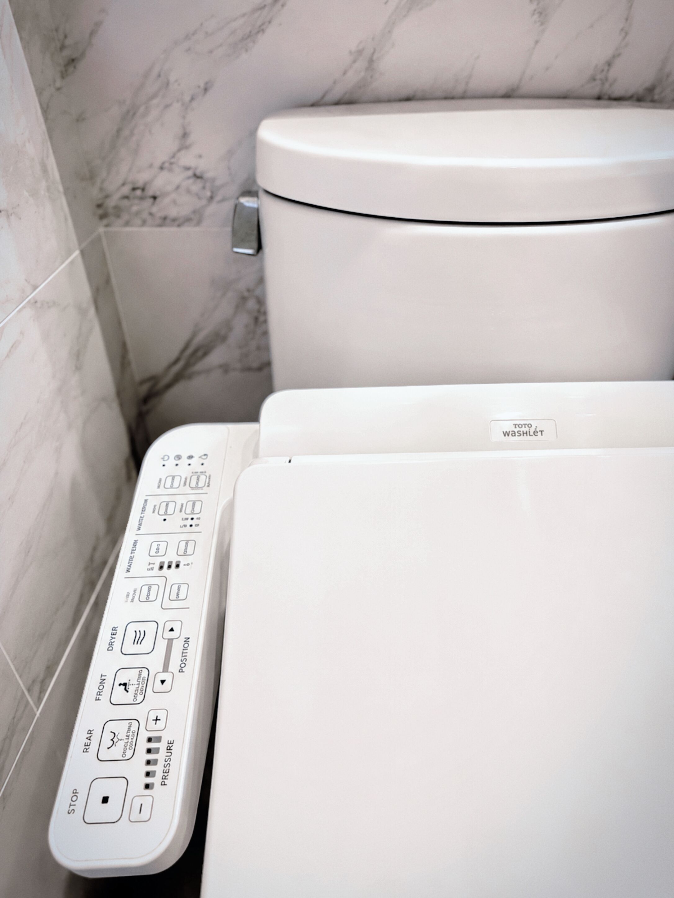 A modern toilet with a control panel featuring multiple buttons for functions like water temperature, pressure, and drying.