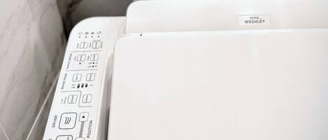 A modern toilet with a control panel featuring multiple buttons for functions like water temperature, pressure, and drying.