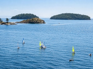 Un paysage côtier avec des voiliers sur une eau calme, entouré d’îles boisées.
