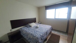 Une chambre à coucher avec un lit, une fenêtre et un climatiseur fixé au mur.