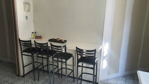 Un coin repas avec une table blanche et quatre chaises noires. On peut voir un plateau contenant des aliments sur la table.