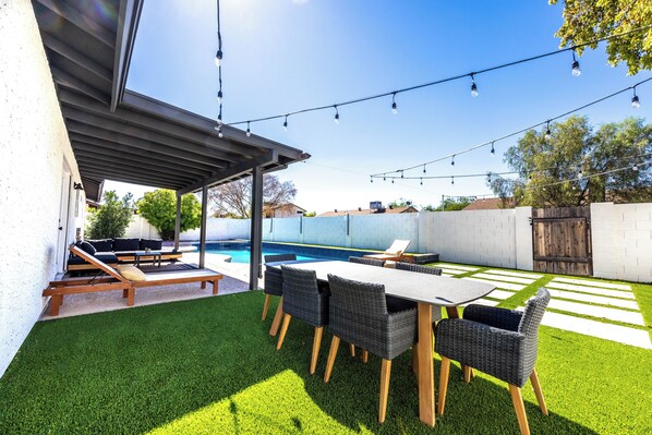 Eine Außenpatio mit Pool, Kunstrasen und Gartenmöbeln.
