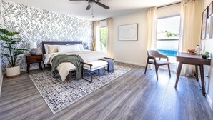 A bedroom with a bed, bedside tables, a desk, a chair, a ceiling fan, a large window with curtains, and a potted plant. - MUST SEE! Heated Jacuzzi w/ Pool! Newly Remodeled! Mid-Century Modern Decor!  (Chandler)
