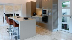 A modern kitchen with a central island, stainless steel appliances, and a glass door leading to a balcony.