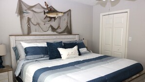 A bed with a striped bedspread, a headboard, and decorative wall art. - Bayside Bliss at Kontiki (Rockport)