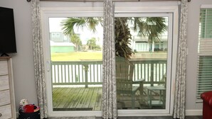Ein Zimmer mit einer Schiebetür zu einer Terrasse, einer roten gepolsterten Bank, einem Fernseher und einer Spielzeugtasche.