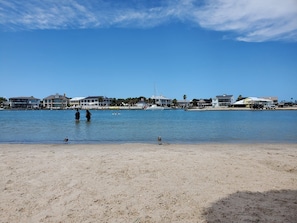 Ein Strand mit freiem Blick auf das Meer und einer Reihe von Häusern im Hintergrund.