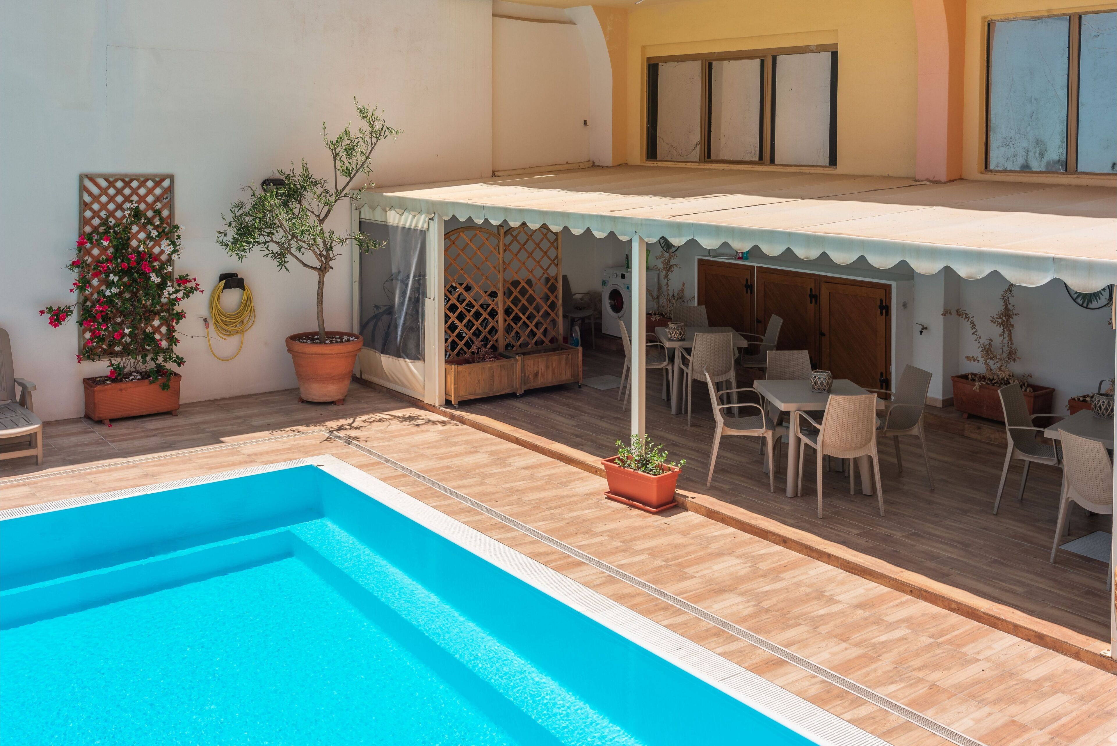 A pool area with a covered seating area and outdoor furniture.