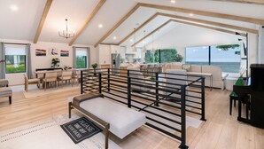 Een ruime woonkamer met hoge plafonds, een eethoek, een keuken en uitzicht op zee.