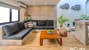 A modern living room with a sectional sofa, a wooden coffee table, and potted plants. - 3br - Exclusive Townthouse - Private Rooftop Pool (Tulum)