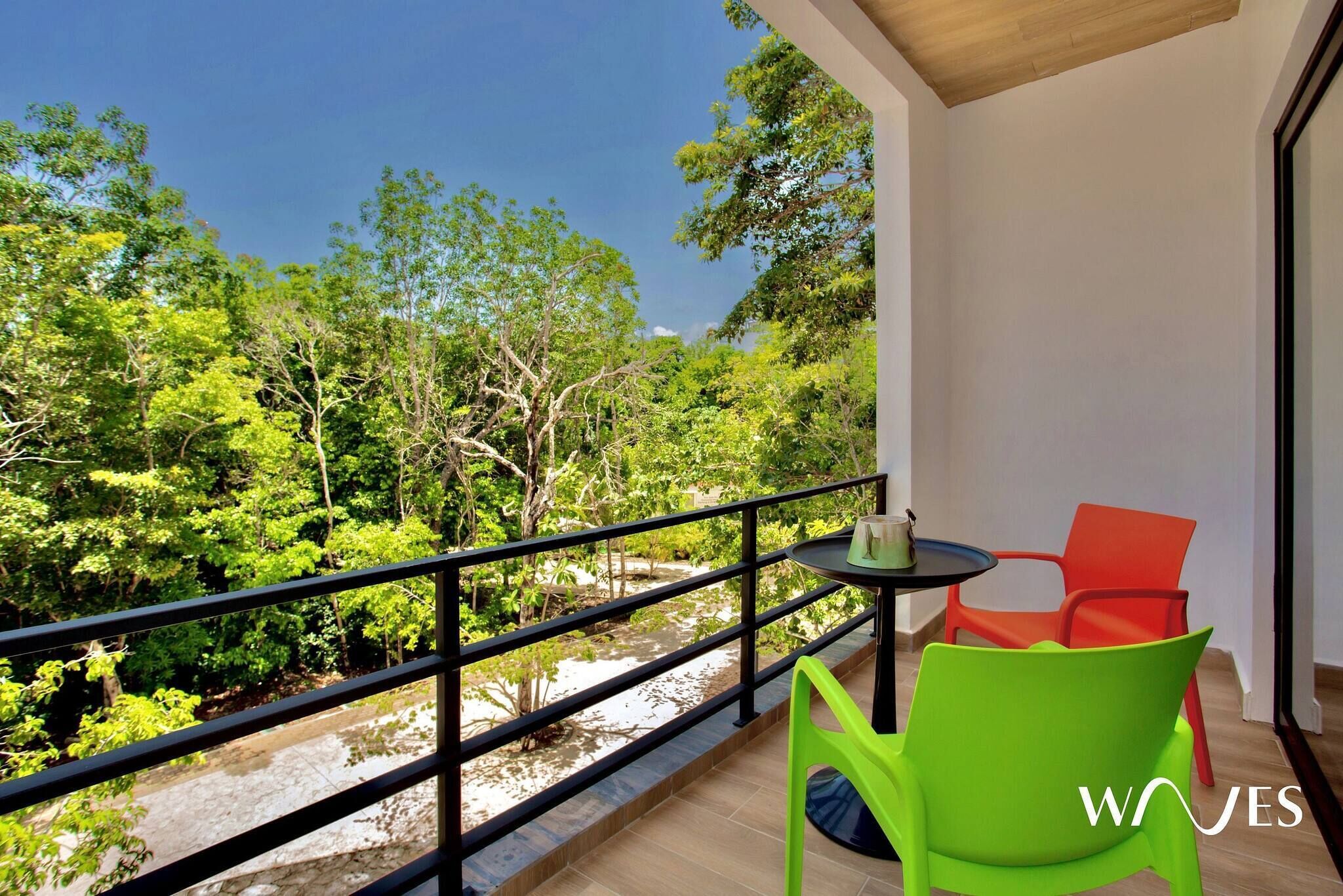 A balcony with a table and chairs, overlooking a lush green landscape.
