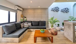 Una sala de estar moderna con un sofá modular, una mesa de centro de madera y plantas en macetas.