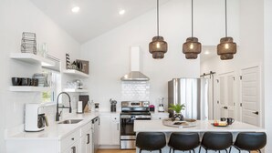 A modern kitchen with white cabinetry, a stainless steel stove, and a central island with bar stools. - Grand Lake View with Outdoor TV, Fireplace, Hot Tub & Game Room Free Attractions Tickets_Cmty Pool (Kimberling City)