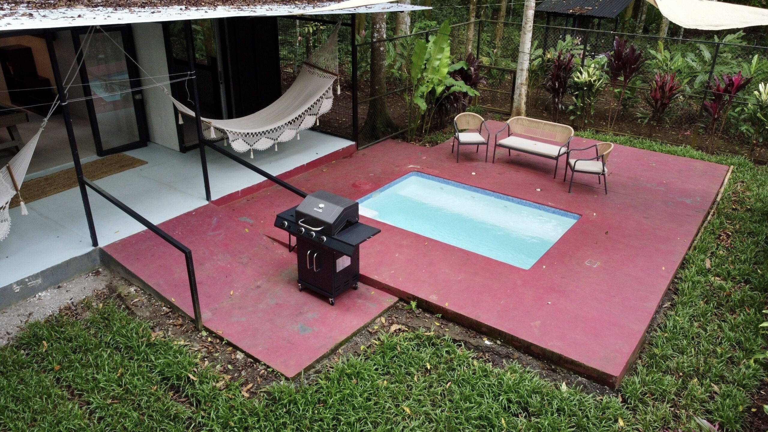 A backyard with a swimming pool, a hammock, and outdoor furniture.