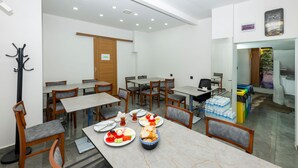 A dining area with tables and chairs, a coat rack, and a door. - Mayza Otel (Istanbul)