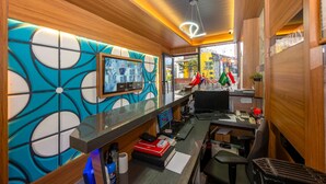 A modern reception area with a wooden interior, a large digital screen, and a desk with a computer and telephone. - Mayza Otel (Istanbul)