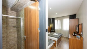 A hotel room with a shower, a bed, a desk, and a TV. - Mayza Otel (Istanbul)