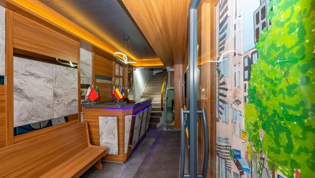 A reception area with a wooden reception desk, marble wall panels, and a staircase leading to upper floors. - Mayza Otel (Istanbul)