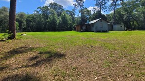 A house with a large lawn and trees in the background.