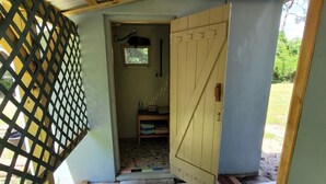 A covered outdoor area with a wooden door, a small window, and a metal roof.