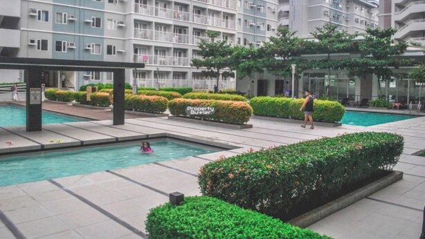 Un immeuble d’appartements moderne doté de nombreux balcons, d’une piscine et d’un aménagement paysager bien entretenu.