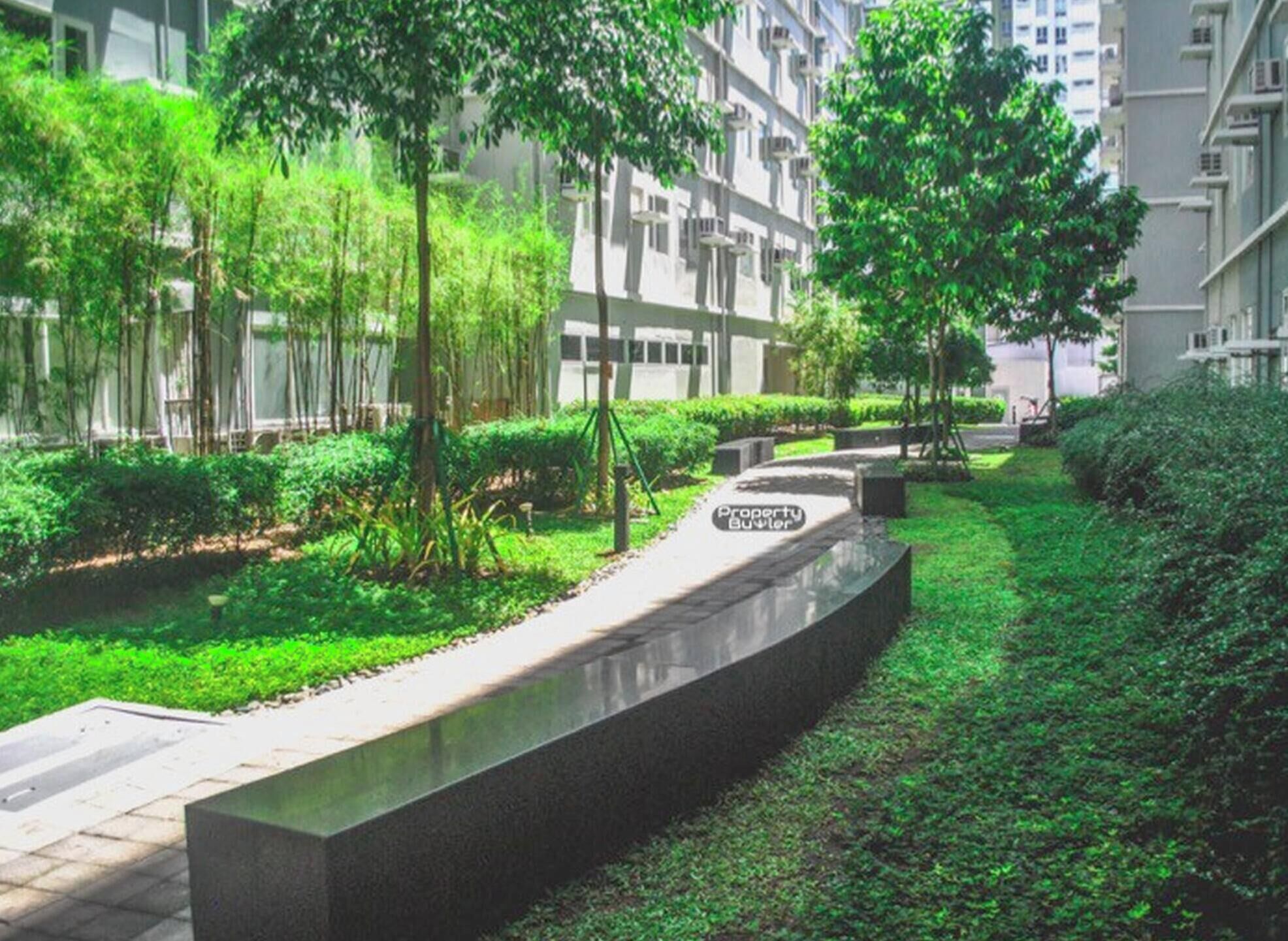A pathway in a residential area with greenery and modern buildings in the background.
