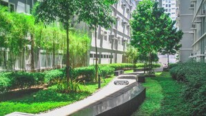 Un chemin dans un quartier résidentiel, bordé de verdure et avec des bâtiments modernes en arrière-plan.
