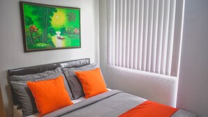 Une chambre à coucher avec un lit, deux oreillers, une couverture, un tableau et une fenêtre avec des stores.