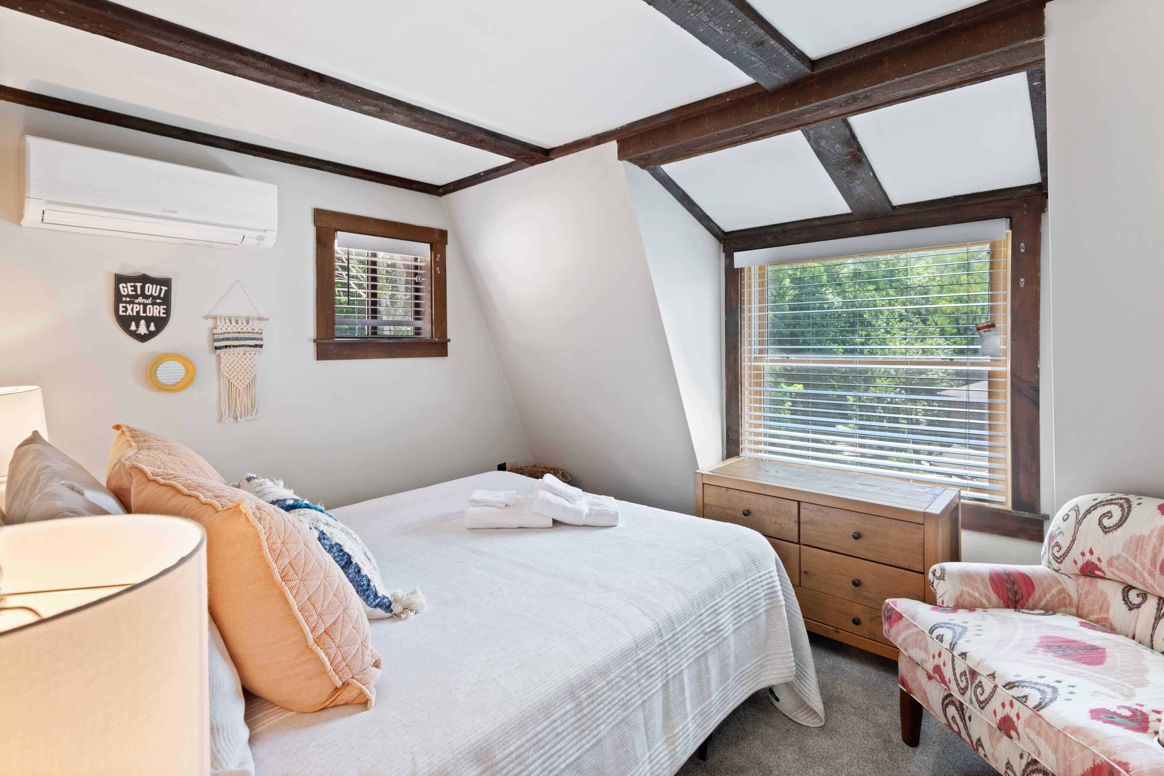 Un dormitorio con cama, mesita de noche, silla y ventana con persianas.