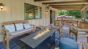 A covered outdoor seating area with a fire feature, wooden furniture, and a view of the outdoors. - Walk to Downtown Banner Elk | Hot Tub, Movie Room & Game Room | Sleeps 17 (Banner Elk)