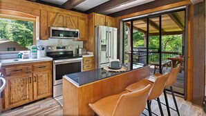 A modern kitchen with wooden cabinets, stainless steel appliances, and a large island with seating. - Walk to Downtown Banner Elk | Hot Tub, Movie Room & Game Room | Sleeps 17 (Banner Elk)