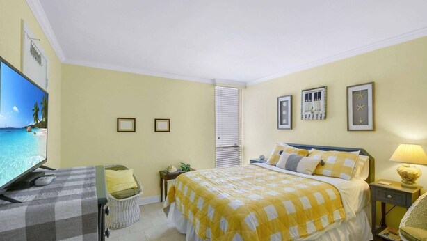 A hotel room with a bed, a television, a small table, and a chair. - Villa 453 - fantastic condo close to pool and beaches (Jekyll Island)