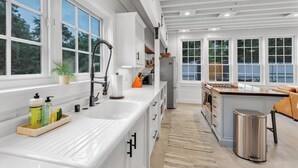 Una cucina moderna con mobili bianchi, un'isola grande e vista sull'esterno.