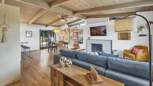 Ein geräumiges Wohnzimmer mit Holzboden, einem blauen Sofa, einem Holztisch und einem Essbereich mit Stühlen und einem Tisch.