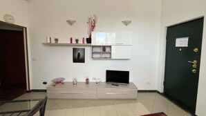 A modern living room with a flat-screen TV, a coffee table, and decorative items on shelves. - Nice Apartment With sea View in Genoa (Genoa)