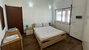 A bedroom with a wooden bed, bedside tables, a window with bars, and a radiator. - Nice Apartment With sea View in Genoa (Genoa)
