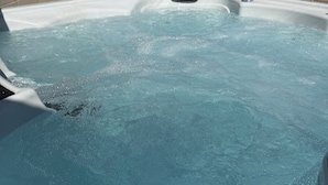 Ein Whirlpool mit sprudelndem Wasser, umgeben von einer Ziegelwand und Pflanzen.