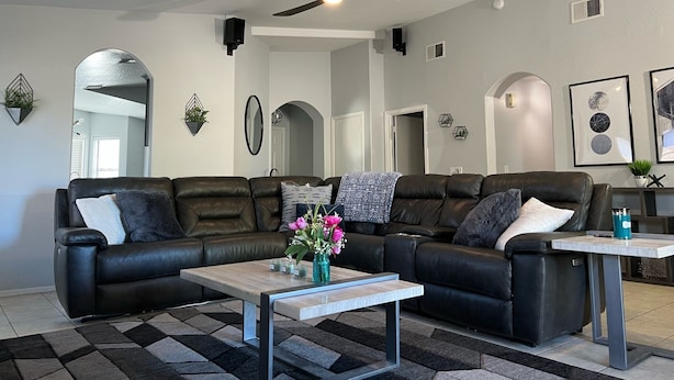 Ein modernes Wohnzimmer mit Ecksofa, Couchtisch und Deckenventilator.