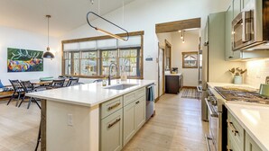 A modern kitchen with a large island, built-in appliances, and a dining area with chairs and a table. - Mountain Views: Luxurious Grand Lake Escape! (Grand Lake)
