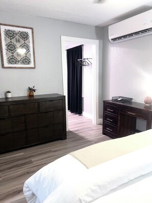Relax in a stylish room with a large bed, dresser, and desk, featuring a beautiful piece of artwork on the wall.