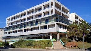 Ein mehrstöckiges Hotel mit Balkonen, einem überdachten Eingang und blauem Himmel.