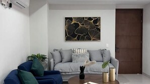 Una sala moderna con un sofá gris, un sillón azul y una mesa de centro.