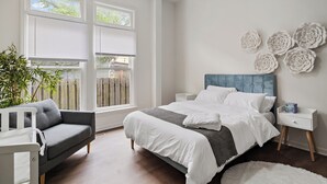 A bedroom with a bed, a gray sofa, a white nightstand, and a large window with blinds. - ⭐Modern 2 Bedroom Unit ⭐ Convenient ⭐ Near Downtown, Convention & Hospitals ⭐ (Indianapolis)