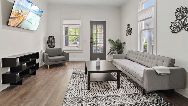 A modern living room with a grey sofa, a coffee table, and a flat-screen TV on the wall. - ⭐Modern 2 Bedroom Unit ⭐ Convenient ⭐ Near Downtown, Convention & Hospitals ⭐ (Indianapolis)